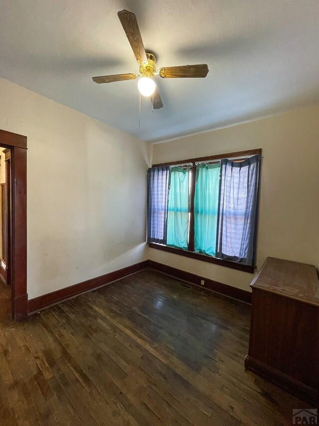 unfurnished room with dark wood finished floors, baseboards, and ceiling fan