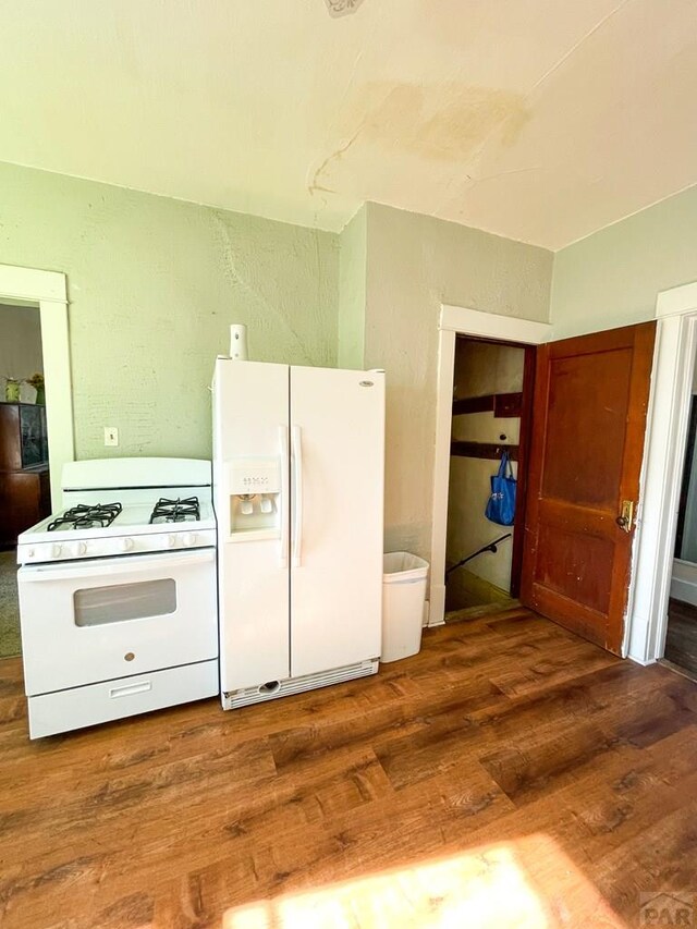 kitchen with white appliances, dark wood-type flooring, and a textured wall