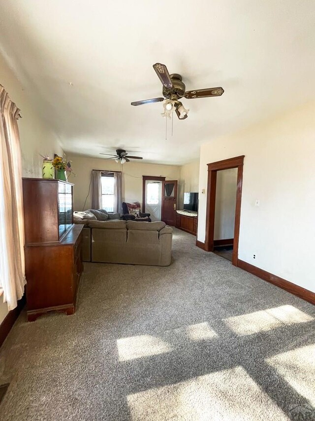 unfurnished living room featuring carpet floors, a ceiling fan, and baseboards