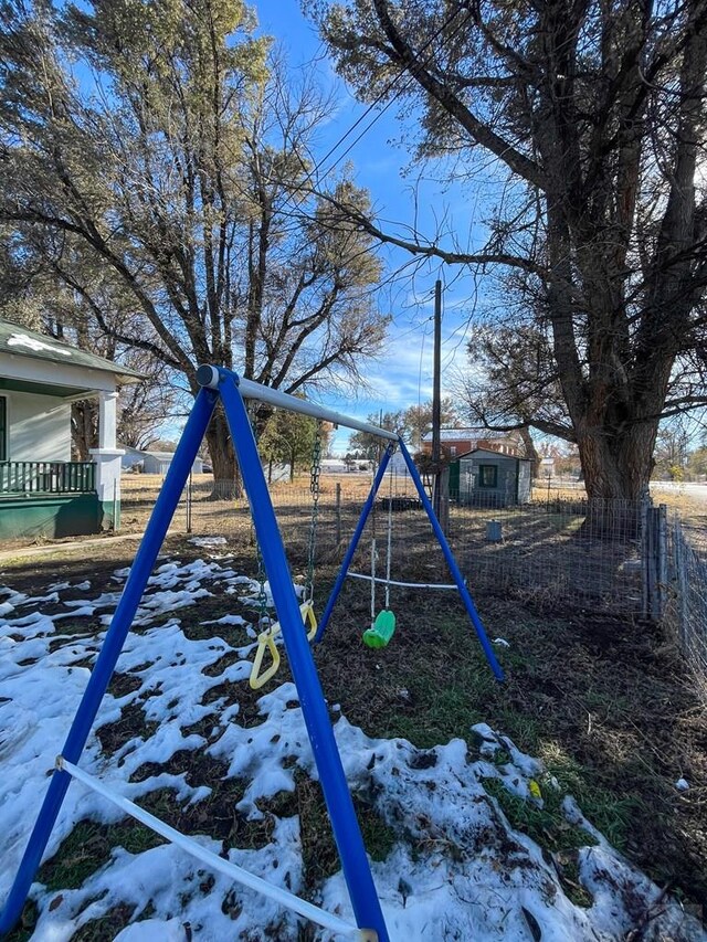 yard layered in snow featuring a playground and fence