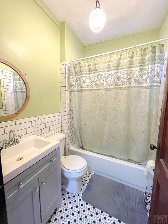 full bath featuring shower / tub combo, toilet, tile patterned flooring, vanity, and tile walls