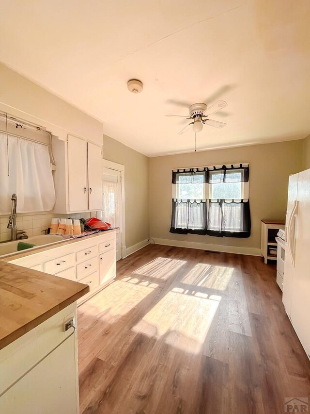 kitchen featuring white appliances, butcher block countertops, a sink, white cabinets, and light wood finished floors