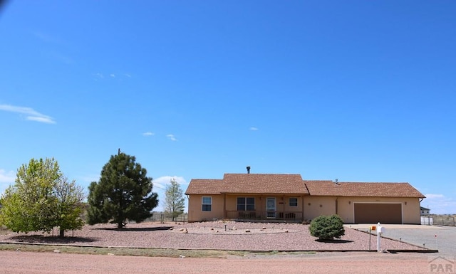 ranch-style house featuring stucco siding, an attached garage, and driveway