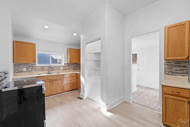 kitchen with light wood-style floors, tasteful backsplash, light countertops, and a sink