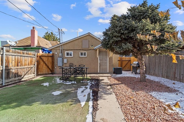 rear view of house featuring a gate, fence, and stucco siding