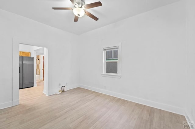 spare room with light wood-style floors, baseboards, and a ceiling fan