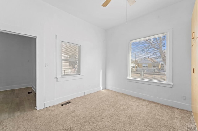 unfurnished room with light carpet, baseboards, visible vents, and ceiling fan