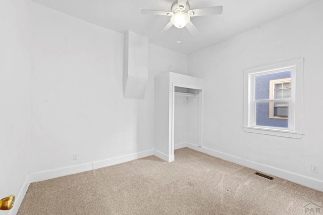 unfurnished bedroom with a closet, visible vents, a ceiling fan, light carpet, and baseboards