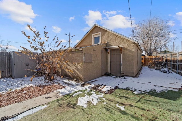 back of house featuring a storage shed, a fenced backyard, an outdoor structure, and stucco siding