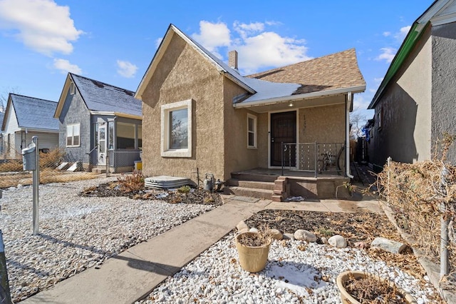 view of front facade featuring a shingled roof and stucco siding