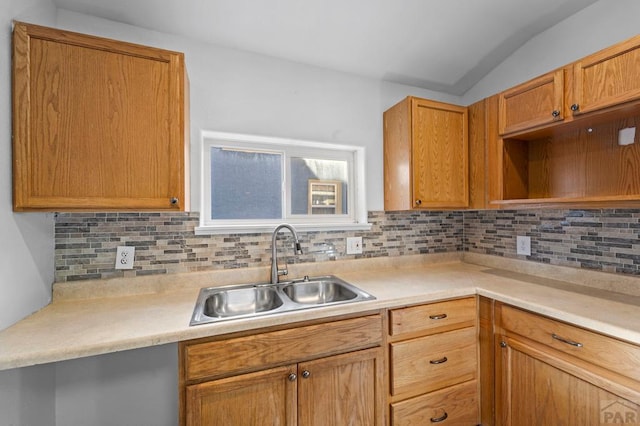 kitchen with brown cabinets, lofted ceiling, light countertops, decorative backsplash, and a sink