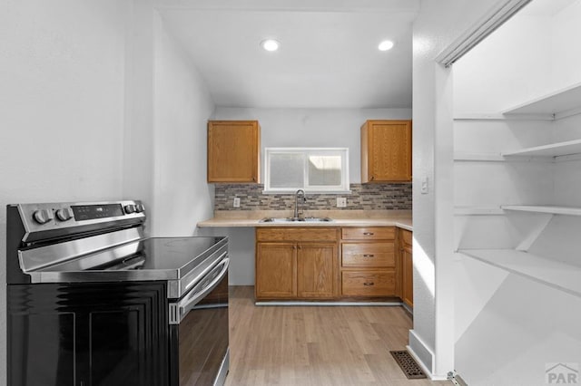 kitchen featuring visible vents, light countertops, stainless steel range with electric cooktop, light wood-style floors, and a sink