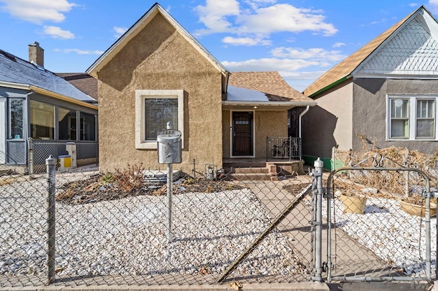 view of front facade with a fenced front yard, a gate, a shingled roof, and stucco siding