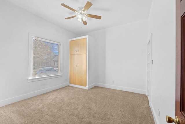 unfurnished room featuring a ceiling fan, light carpet, and baseboards