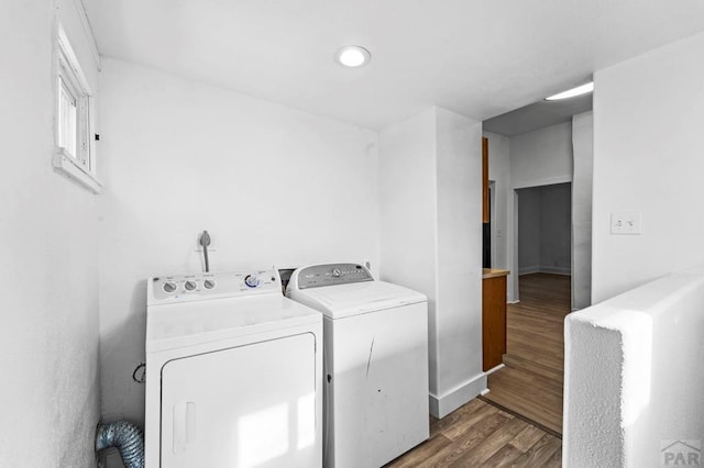 laundry area with laundry area, dark wood-style flooring, washing machine and dryer, and baseboards