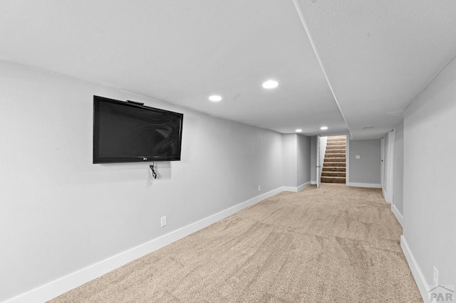 finished basement with recessed lighting, light colored carpet, stairway, and baseboards