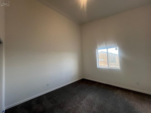 unfurnished room featuring dark colored carpet and baseboards