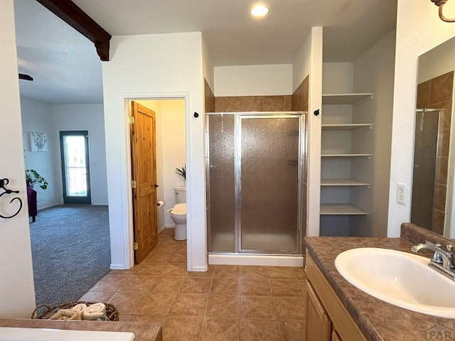 bathroom featuring toilet, vanity, a stall shower, tile patterned floors, and beamed ceiling