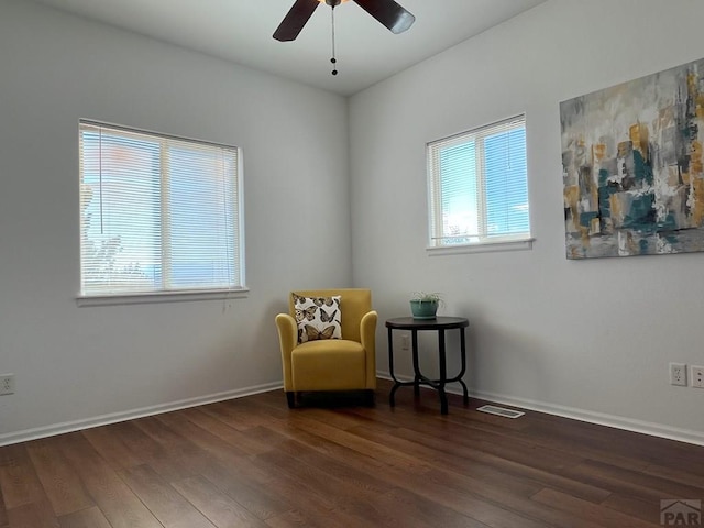 living area featuring ceiling fan, visible vents, baseboards, and wood finished floors