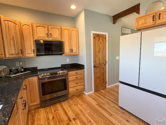 kitchen featuring light wood-style floors, freestanding refrigerator, dark stone counters, and electric range