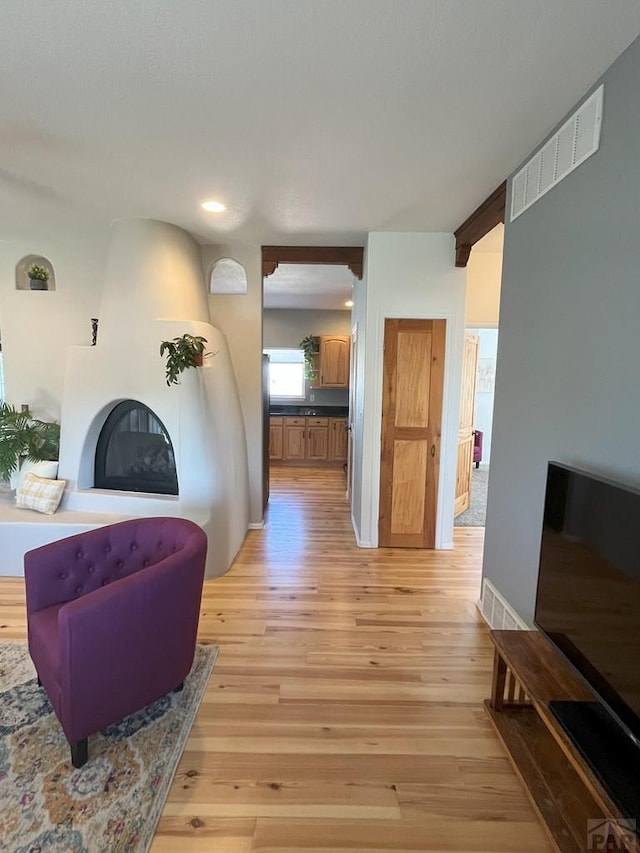 living room featuring light wood-style floors, baseboards, a fireplace, and visible vents