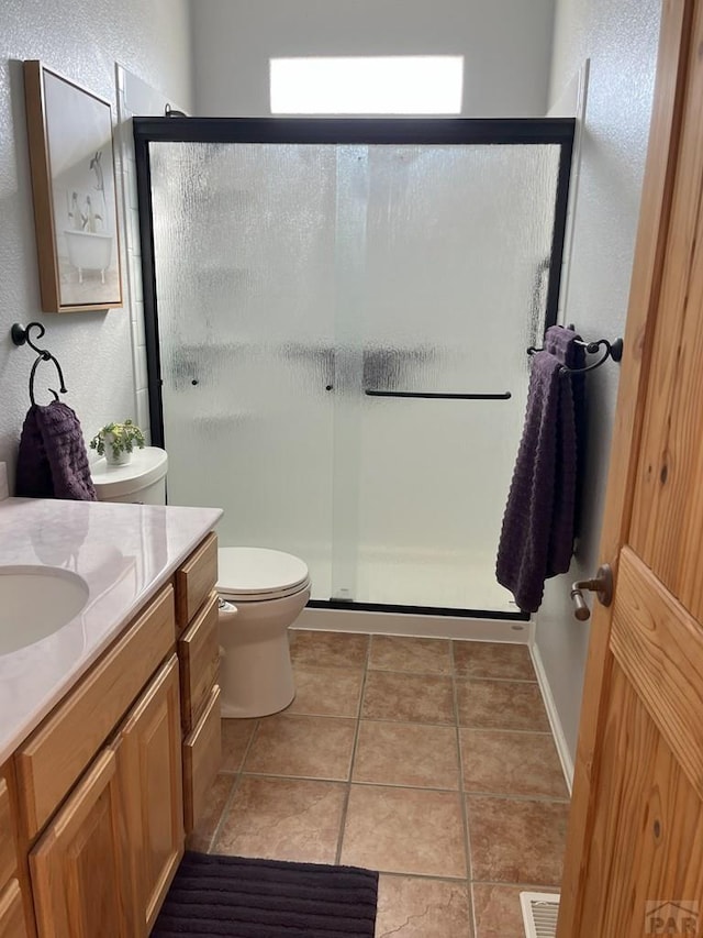 bathroom featuring toilet, a shower stall, vanity, and tile patterned floors