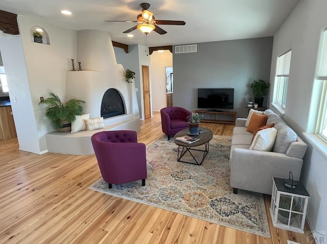 living room with visible vents, a fireplace with raised hearth, a ceiling fan, wood finished floors, and recessed lighting