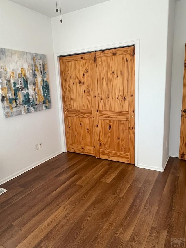 unfurnished bedroom with visible vents, baseboards, and dark wood finished floors