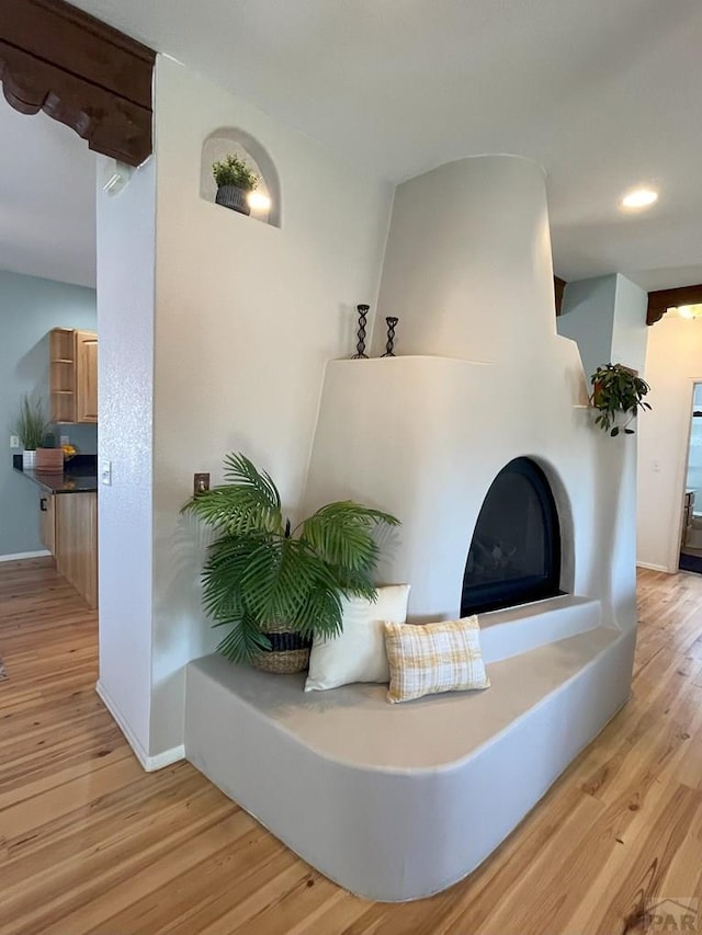 interior space with a fireplace with raised hearth, light wood-style flooring, and baseboards