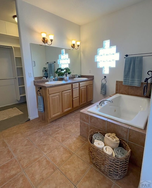 full bath with double vanity, tile patterned flooring, a sink, and a whirlpool tub