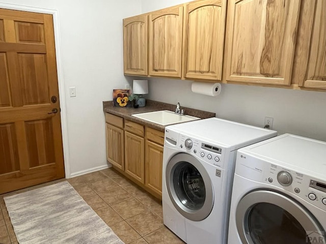 washroom with cabinet space, light tile patterned floors, baseboards, separate washer and dryer, and a sink