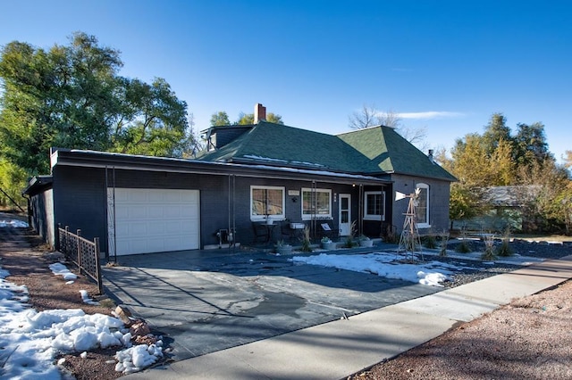 view of front of home featuring covered porch, concrete driveway, a chimney, and an attached garage