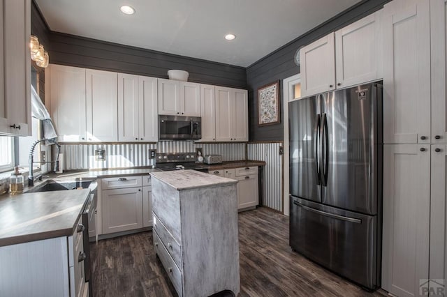 kitchen with dark wood-style floors, a kitchen island, stainless steel appliances, white cabinetry, and a sink