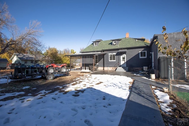 snow covered back of property featuring entry steps and fence