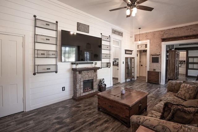 living area with ceiling fan, dark wood-type flooring, and a fireplace