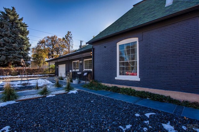 view of snow covered exterior with a garage and brick siding