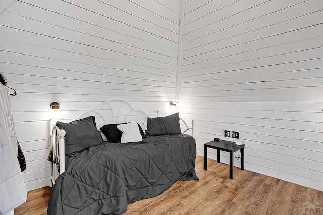 bedroom featuring wooden walls and wood finished floors