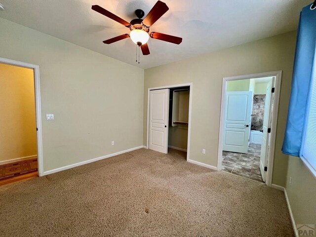 unfurnished bedroom featuring carpet floors, a closet, ensuite bathroom, ceiling fan, and baseboards