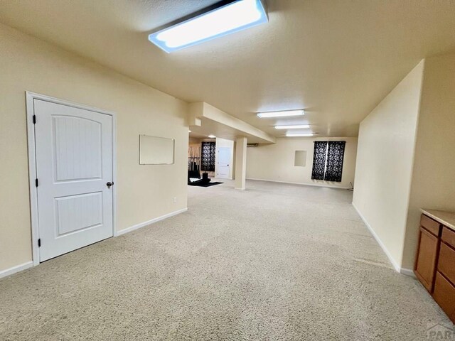 finished below grade area featuring light colored carpet and baseboards