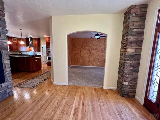 interior space with arched walkways, ceiling fan, light wood finished floors, and baseboards