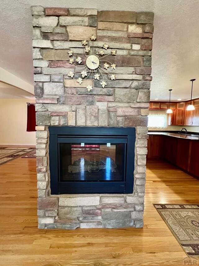 interior details featuring a textured ceiling, a fireplace, and wood finished floors