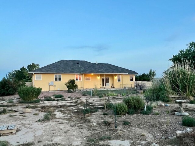 rear view of house featuring fence and stucco siding