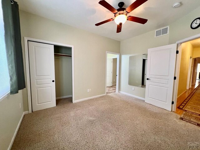 unfurnished bedroom with a closet, visible vents, light carpet, and baseboards