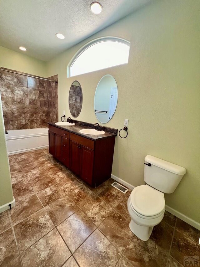 bathroom featuring toilet, a textured ceiling, visible vents, and a sink