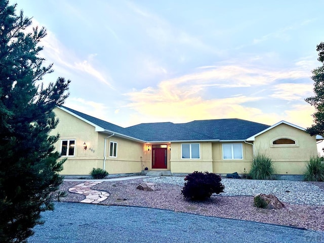 single story home featuring roof with shingles and stucco siding