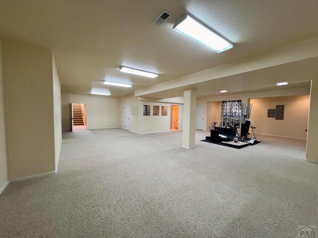 finished basement with baseboards, electric panel, and visible vents