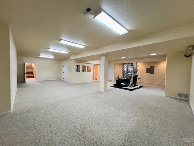 finished below grade area featuring electric panel, visible vents, stairway, and baseboards