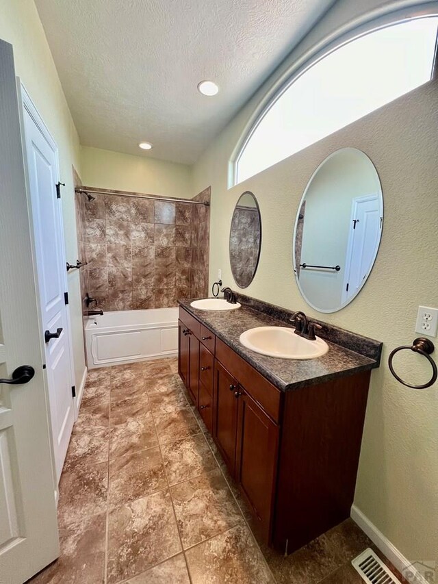 full bathroom with  shower combination, visible vents, a sink, and a textured ceiling