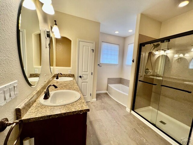 bathroom featuring a garden tub, a stall shower, and a sink