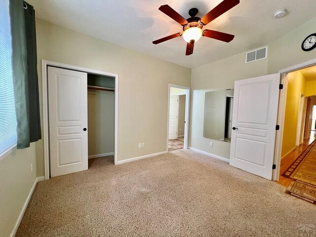 unfurnished bedroom with light carpet, a closet, visible vents, and baseboards